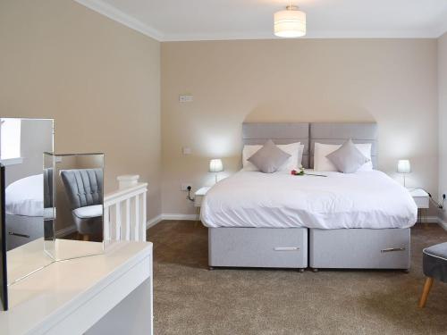 a bedroom with a large white bed and a chair at Faodail-uk34218 in Aberfoyle