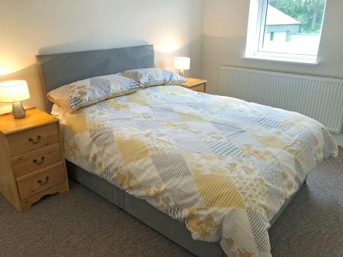 a bedroom with a bed and a night stand with two lamps at Forest Walk in Coleford