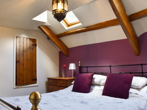 a bedroom with a large bed with purple walls at Pineview Cottage in Downderry