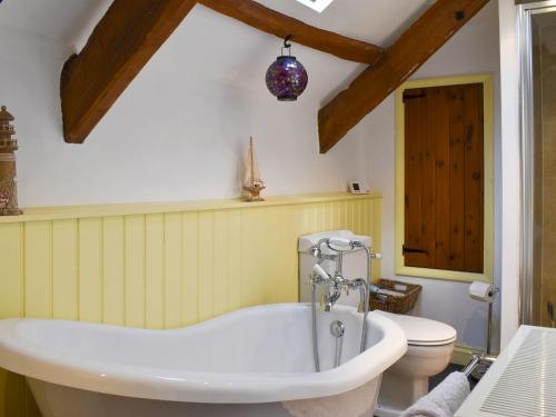 a bathroom with a tub and a toilet at Pineview Cottage in Downderry