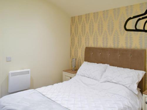 a bedroom with a white bed with a wooden headboard at Shepherds Hut 1 At Laddingford - Uk32531 in Yalding