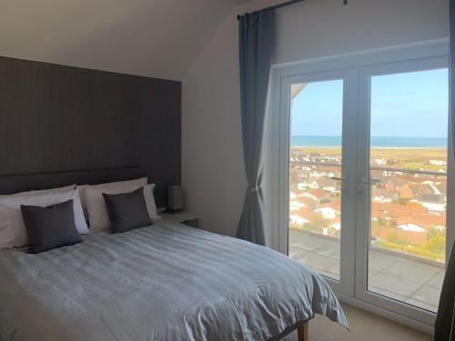 a bedroom with a bed and a large window at Atlantic View in Westward Ho