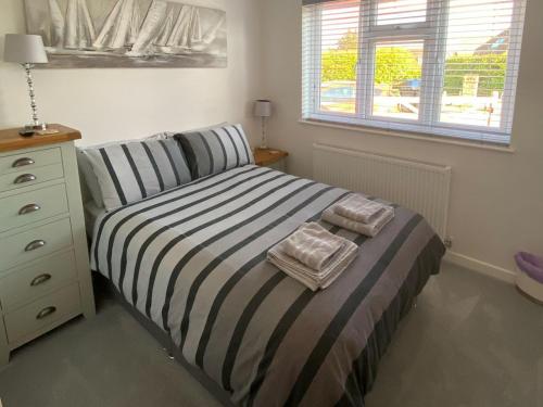 a bedroom with a striped bed with a dresser and a window at Rainbows End in Saint Lawrence