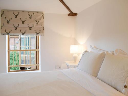 a white bedroom with a bed and a window at Pepperpot Lodge in Baschurch