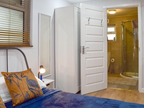 1 dormitorio con cama, ducha y puerta en The Studio en Long Hanborough