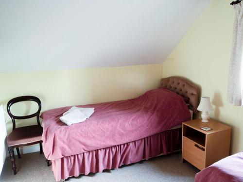 um pequeno quarto com uma cama rosa e uma cadeira em The Small Barn em Wood Norton