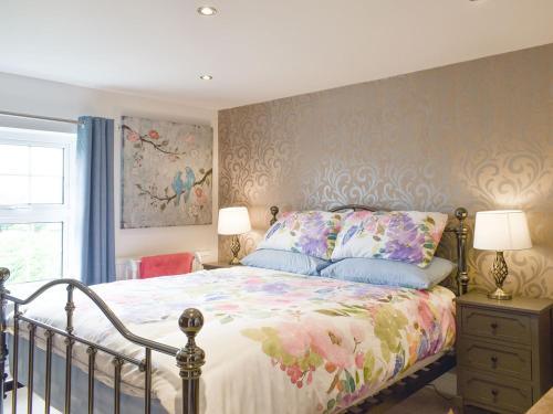 a bedroom with a bed with a floral bedspread at Beck Cottage in Mildenhall