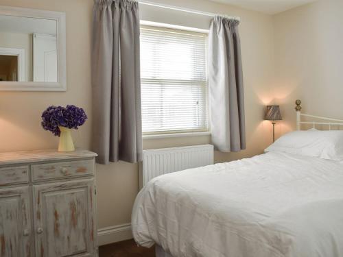 a bedroom with a white bed and a window at Bank Side in Leyburn