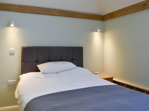 a bedroom with a large bed with a large headboard at The Granary in West Hoathley