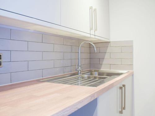 a kitchen with a stainless steel sink and white tiles at The Classroom in Bourton