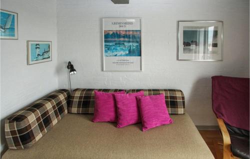 a couch with pink pillows in a living room at Cute Apartment In Samsø in Ballen