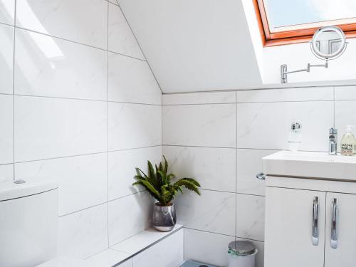 a white bathroom with a potted plant in it at The Old Exchange in Market Bosworth