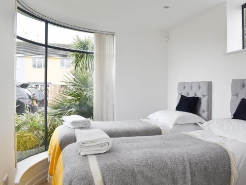 two beds in a white room with a window at The Beach Stop in East Preston