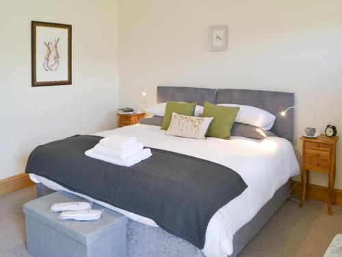 a bedroom with a large bed with green pillows at Lapwing Cottage in Longframlington