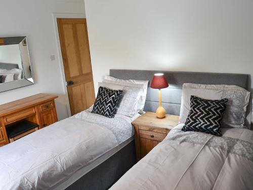 a bedroom with two beds and a table with a lamp at Church Farm House in Sea Palling