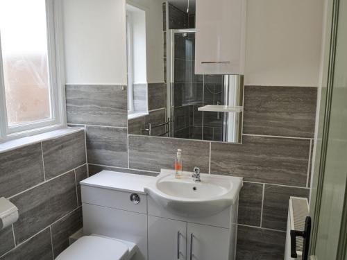 a bathroom with a sink and a toilet and a mirror at Church Farm House in Sea Palling