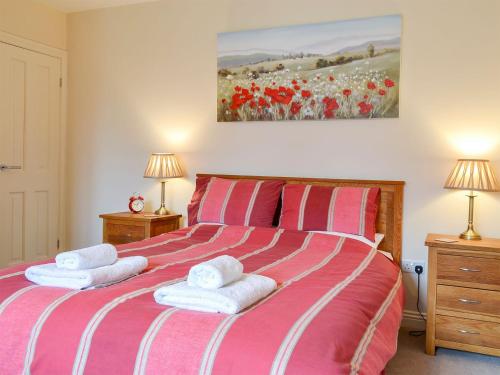a bedroom with a red and white bed with towels on it at Croft Cottage 1 - Uk10587 in Stillington