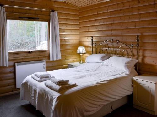 a bedroom with a bed in a log cabin at Holme Garth Lodge in Legbourne