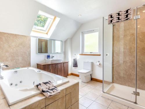 a bathroom with a tub and a shower and a toilet at Lochside House - S4532 in Letterfearn