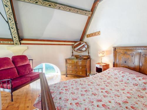 um quarto com uma cama e um sofá vermelho em St Andrews Church em East Barkwith