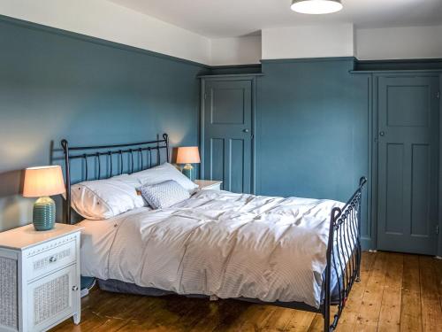 a bedroom with a bed and a blue wall at Broads Rest in Martham