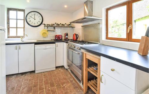 a kitchen with white appliances and a clock on the wall at Awesome Home In St Pierre En Auge in Vieux-Pont-En-Auge