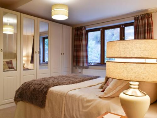 a bedroom with a bed and a lamp and windows at Quarry Cottage in Highpeak Junction