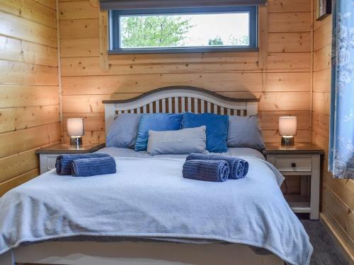 a bedroom with a bed with blue pillows on it at Pine Lodge - Uk30007 in Lindal in Furness