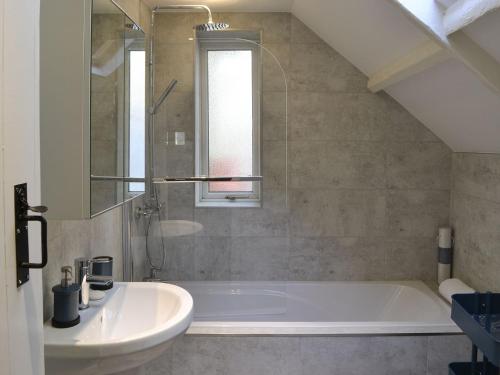 a bathroom with a white tub and a sink at Horsley Cottage in Rochester