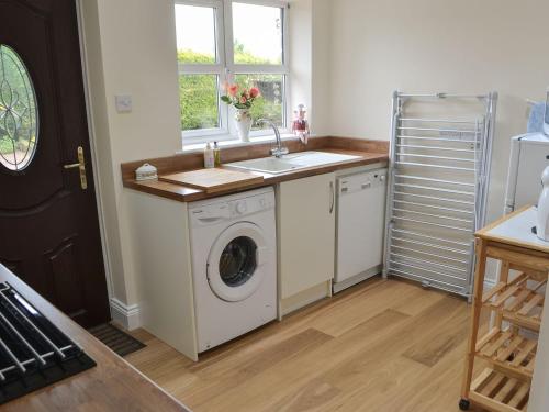 a kitchen with a washing machine and a sink at The Gin Gan Cottage in Ryal