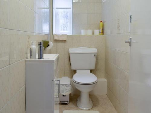 a white bathroom with a toilet and a sink at Sisial Y Gwynt in Llanferres
