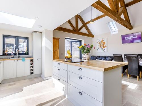 a kitchen with white cabinets and a bar with a wine cellar at The Old Dairy in Shipton under Wychwood
