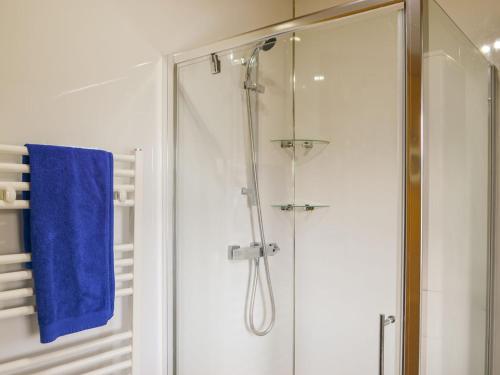 a bathroom with a shower with a blue towel at Cairnswood in Swarland