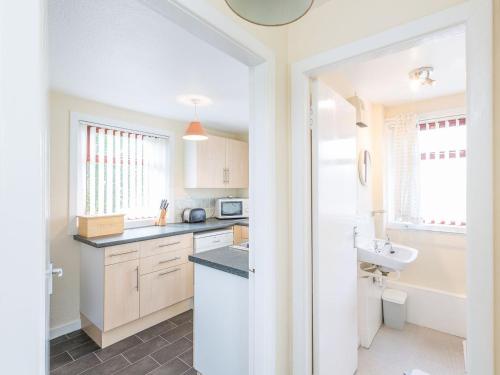 a kitchen with white cabinets and a sink at Balnain 1 in Cononbridge