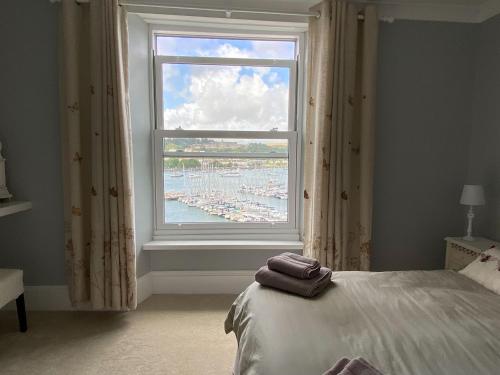 een slaapkamer met een raam met uitzicht op een haven bij Riverdene in Kingswear