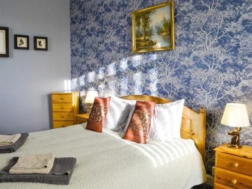 - une chambre avec un lit et du papier peint bleu dans l'établissement Balig Cottage, à Ballantrae