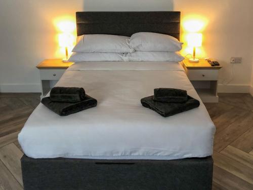 - un grand lit blanc avec 2 serviettes noires dans l'établissement Whinacres Cottage 1894, à Conwy