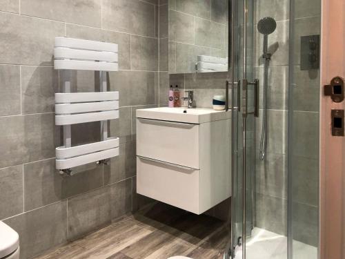 La salle de bains est pourvue d'un lavabo blanc et d'une douche. dans l'établissement Whinacres Cottage 1894, à Conwy
