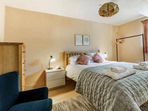 a bedroom with a large bed and a chair at Coach House Retreat - Uk32202 in Burton Bradstock