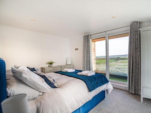 a bedroom with a bed and a large window at Hazelgrove Lodge Barn in Kelbrook