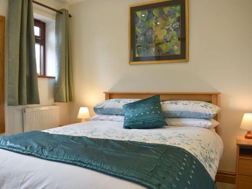 a bedroom with a bed with blue pillows on it at Brooklands Cottage in Bellerby