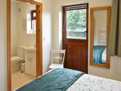 a bedroom with a bed and a bathroom with a mirror at Brooklands Cottage in Bellerby
