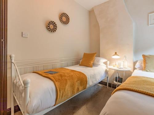 a bedroom with two beds and a clock on the wall at Spring Cottage in Endon