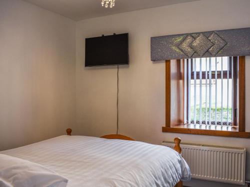 1 dormitorio con 1 cama y TV en la pared en Belger Cottage en Inverallochy