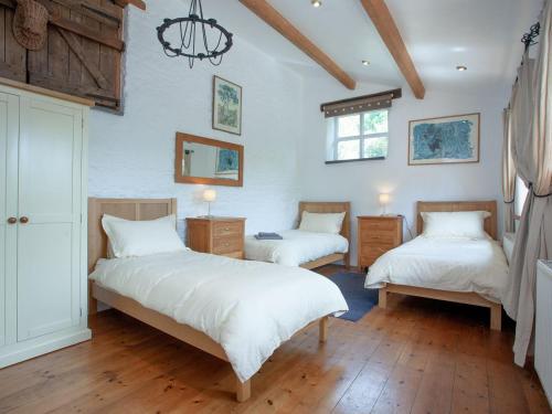 a bedroom with two beds and a chandelier at Higher Broadaford Barn in Ivybridge