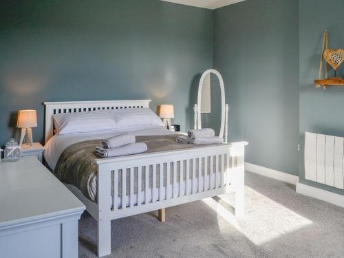 Schlafzimmer mit einem weißen Bett und einem Spiegel in der Unterkunft Broomlands Cottage in Beattock