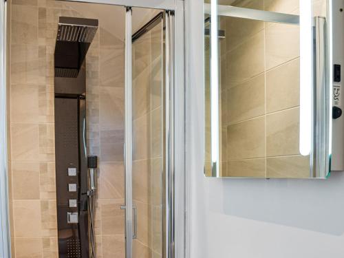 a glass shower door with a mirror in a bathroom at Kinneret Apartment in Silsden