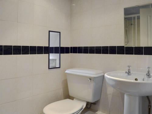 a bathroom with a white toilet and a sink at Cobblestones in Westward