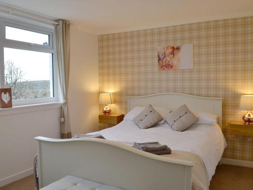 a bedroom with a white bed with two pillows at Cotters Cottage - Uk10922 in Whithorn