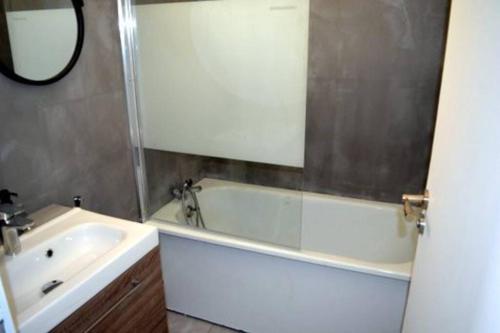 une salle de bain avec une baignoire, un lavabo et un miroir dans l'établissement studio de la plage, à Saint-Cyprien